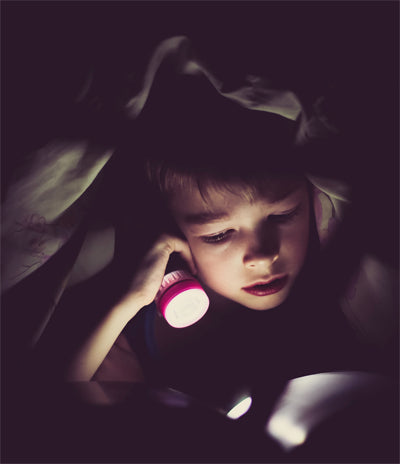Lapsi lukee taskulampun valossa