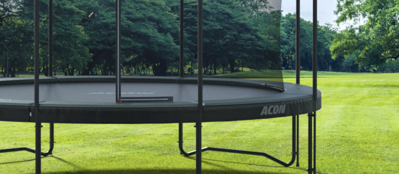Round trampoline with enclosure net at summer in a garden