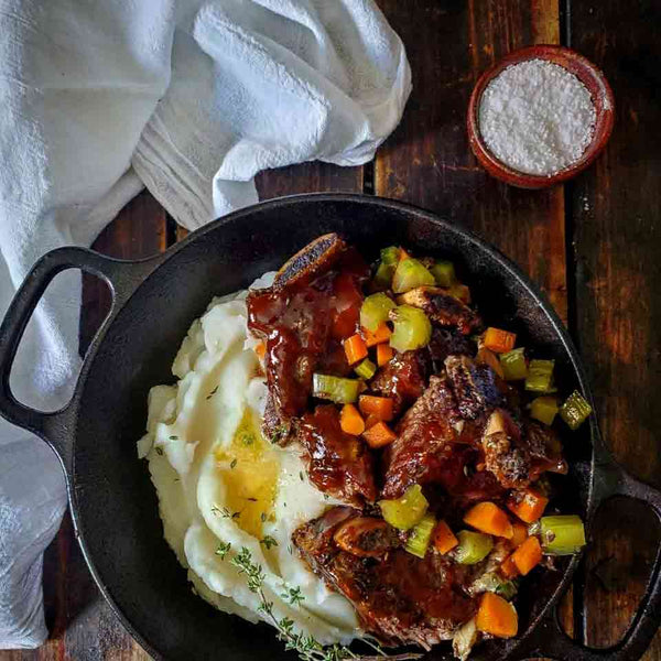 A cast iron pot filled with cola braised short ribs and mashed potatoes.