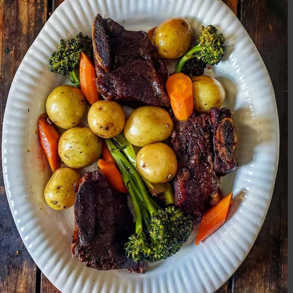 braised short ribs recipe displayed with potatoes, carrots and broccoli on a white plate