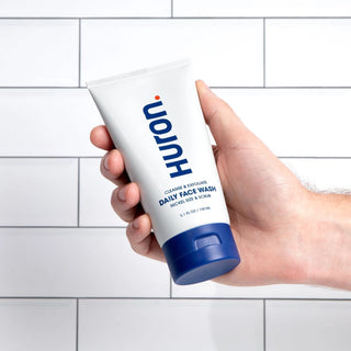 Huron Face Wash in a hand, featuring a white tube with blue accents.
