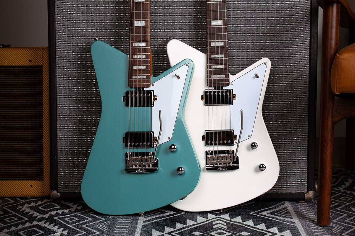 รูปทรงกีต้าร์แบบออฟเซท Mariposa guitars in Dorado Green and Imperial White resting against an amp.