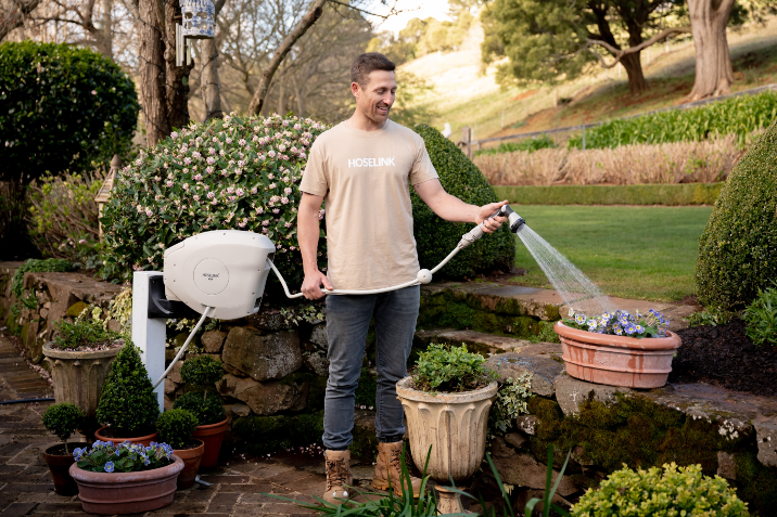 man watering his garden with a retractable hose reel