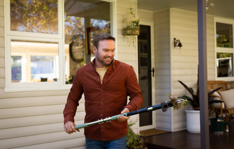 man using stand up weed puller to pull weed from lawn