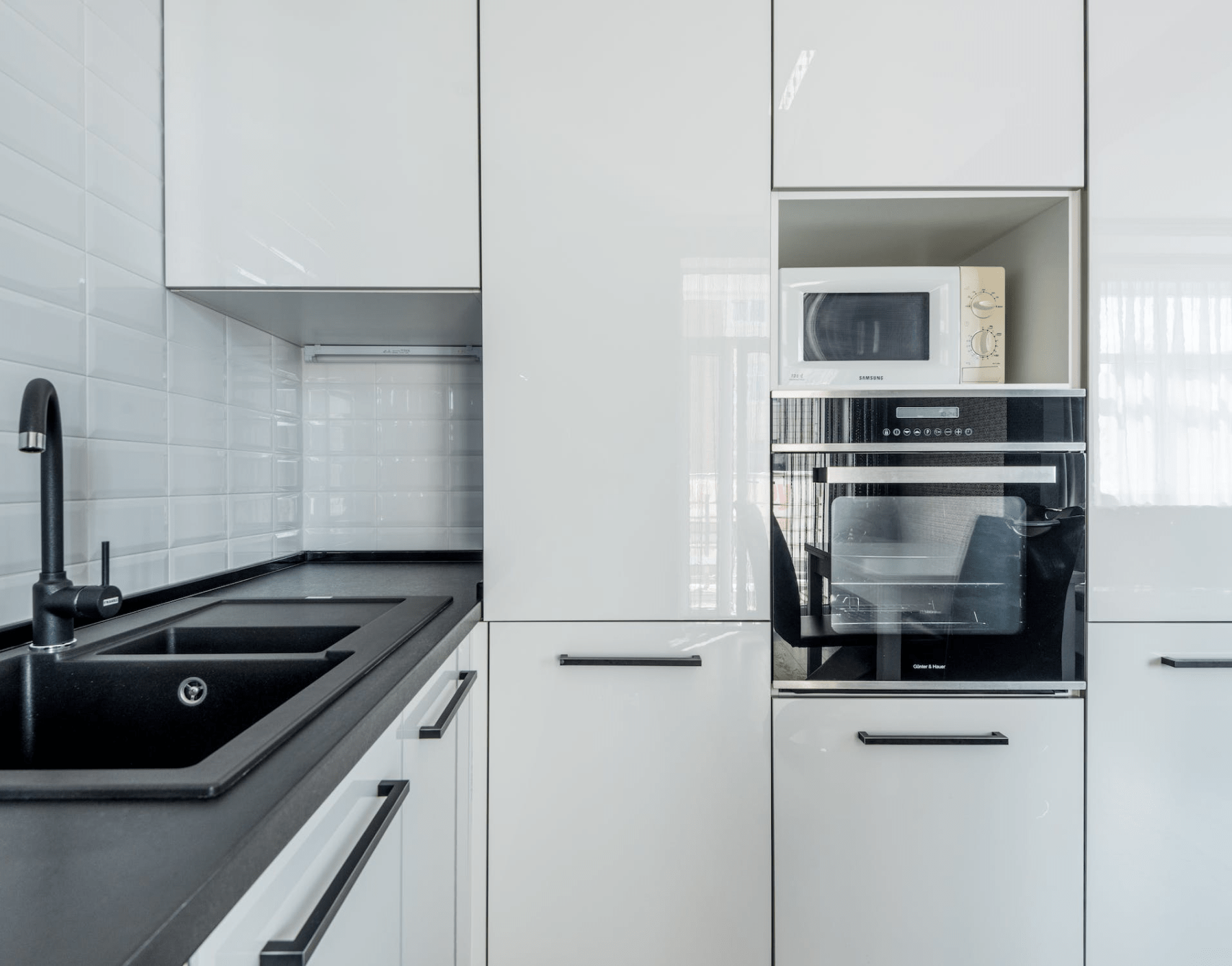 A Contemporary kitchen with white shiny cabinets and sleek black hardware