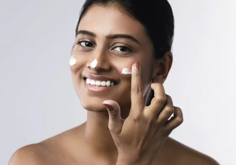 Indian woman applying sunscreen with spf for UV rays protection - Mineral and Chemical sunscreen