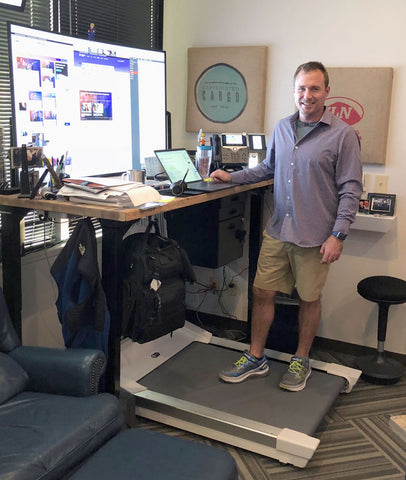 Jonathan Ferebee standing on his Unsit Treadmill Desk, short from back left