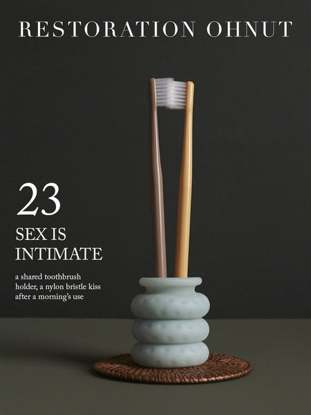 Image of two toothbrushes nestled in an Ohnut. "Restoration Ohnut. 23. Sex is intimate—a shared toothbrush holder, a nylon bristle kiss after a morning’s use."