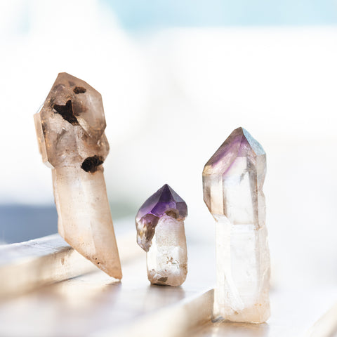 Amethyst scepter crystals sitting on a ledge in front of a bright window