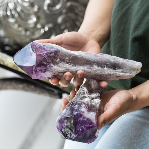 A close up of someone holding two natural purple amethyst crystals from Bahia Brazil
