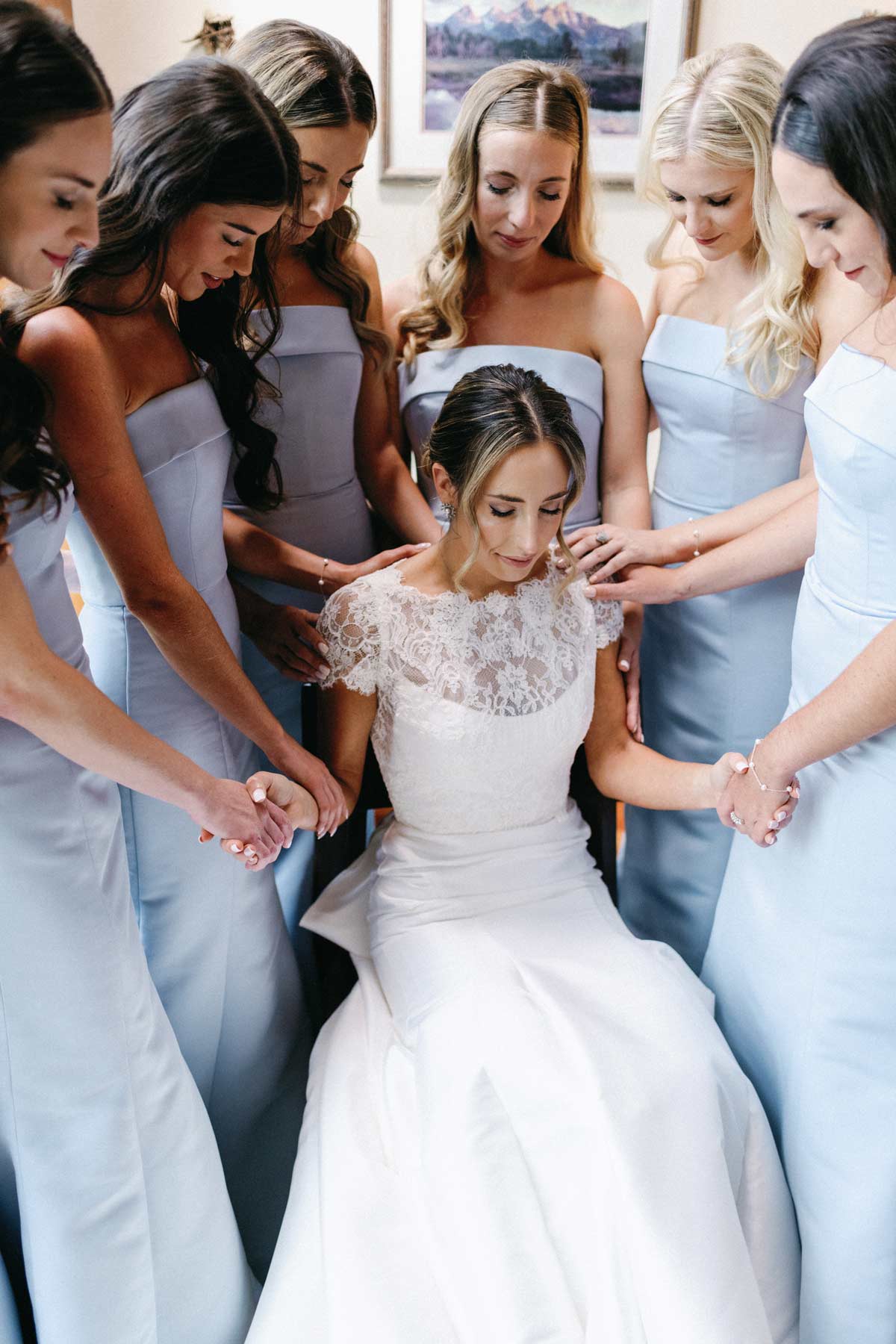 bride sitting in the middle of her bridesmaids who are praying over her