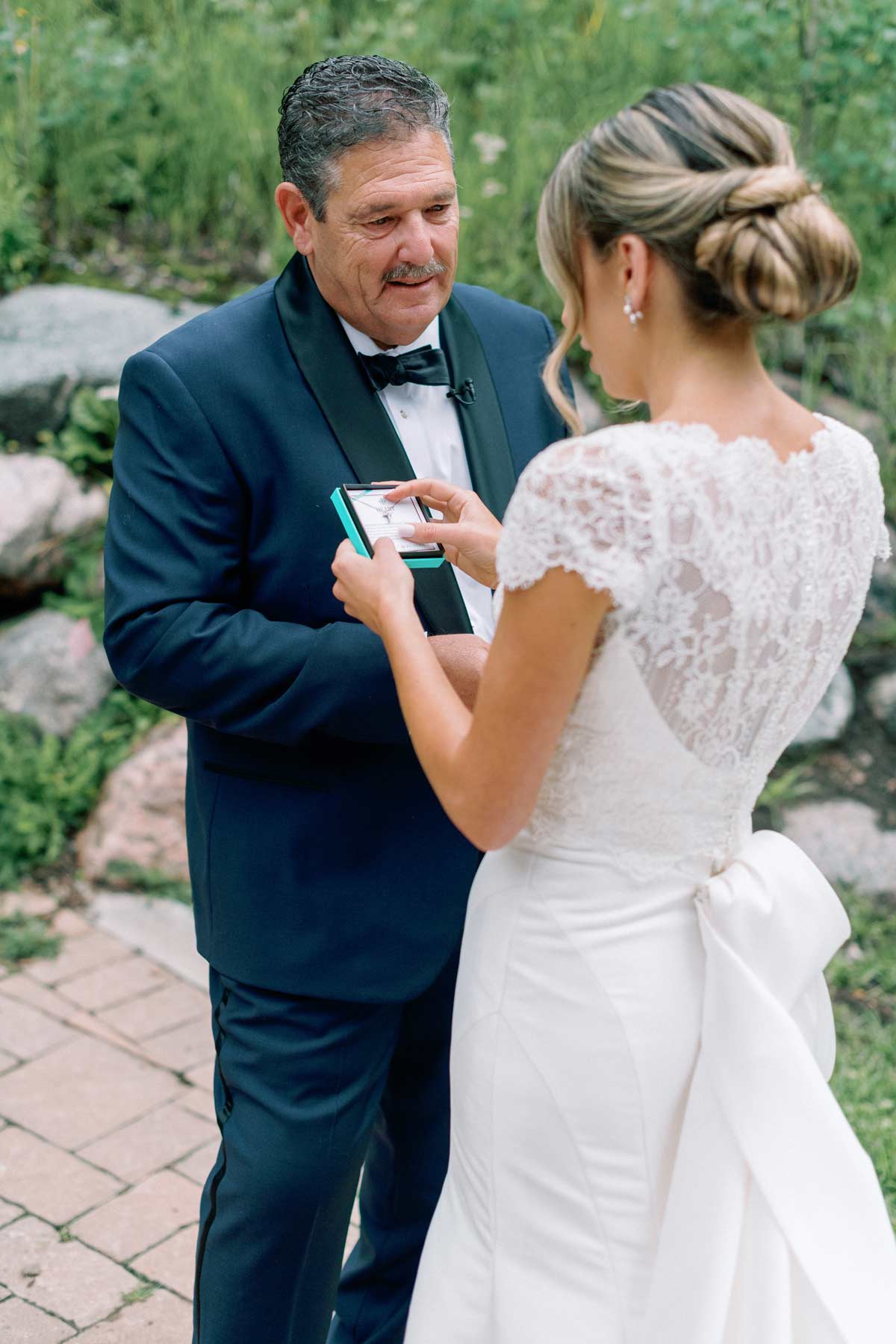 father gives daughter a cross necklace before her wedding ceremony