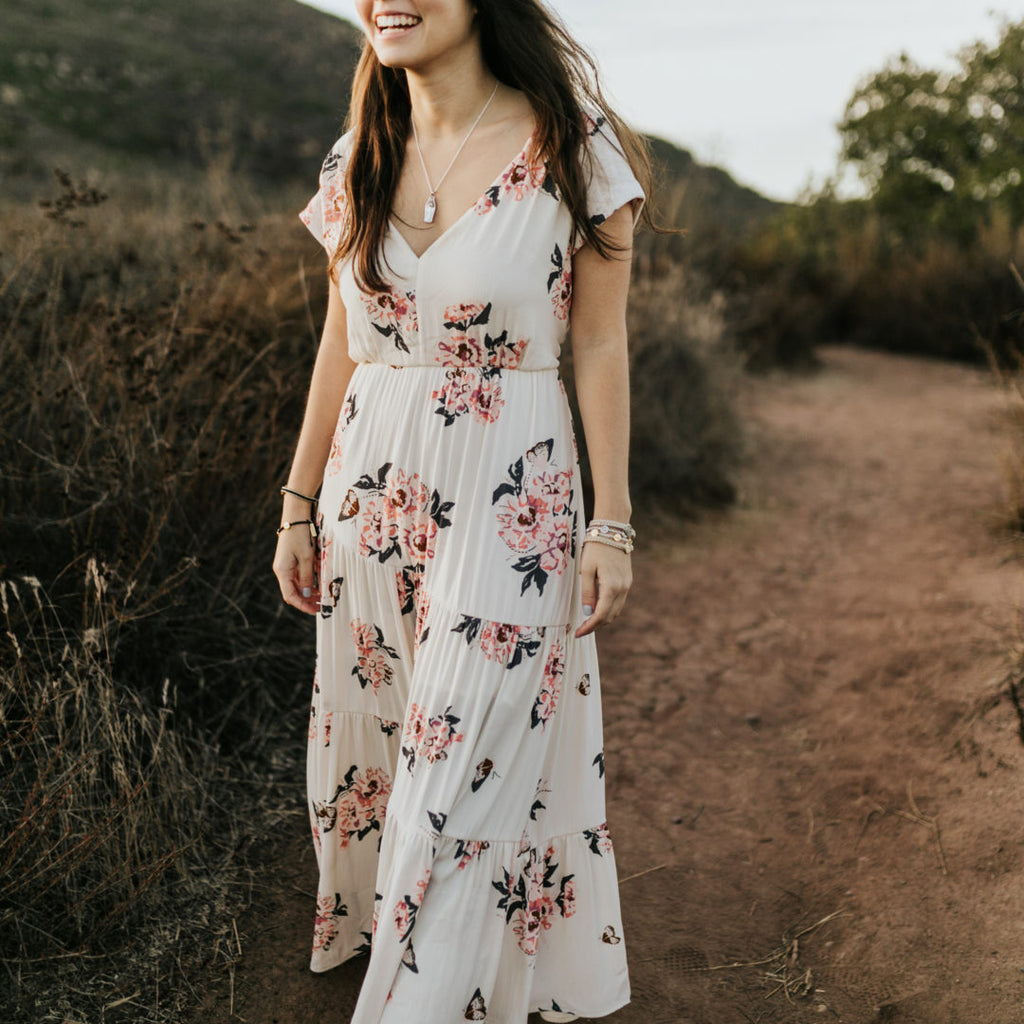 woman in pink flowered white dress wearing a stock of My Saint My Hero Gratitude Blessing bracelets