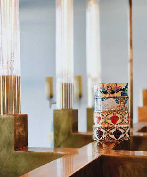 stack of Iconic Jewelry Collection cuff bracelets displayed against background of tall glass candle holders