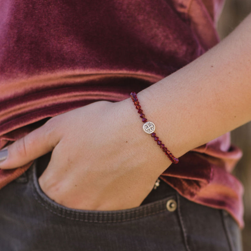 close up of a girl wearing a January ruby and silver tone benedictine Birthday Blessing Bracelet