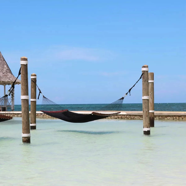 Tuuci Twin Air Lounge hammock is attached to two groynes. In the background there is a small wooden pier.