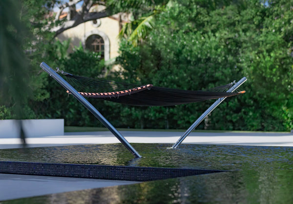 Black TUUCI AIR LOUNGE hammock with a stainless steel frame stands in a pool.