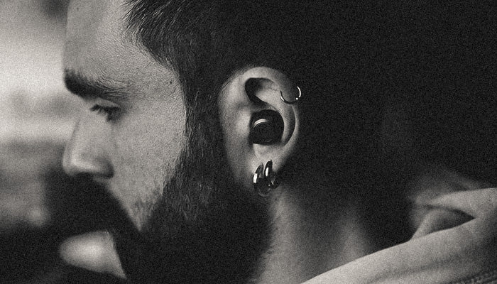 Close-up of a bearded man with piercings on his ear