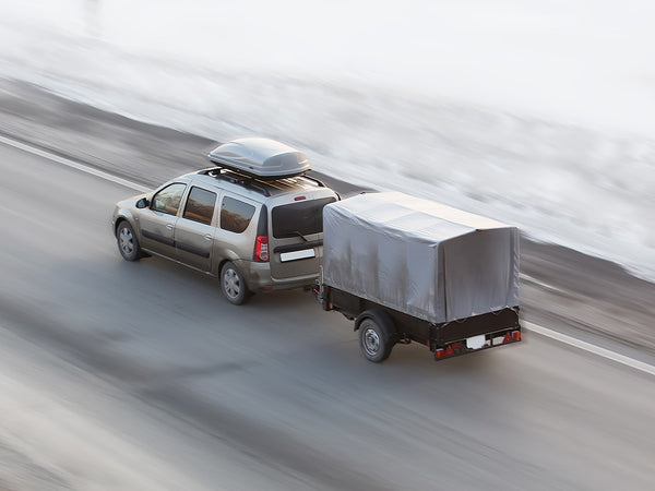  Image of a car driving down the highway with a trailer attached.