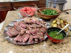 A dinner with steak, chicken, potatoes, salad and watermelon