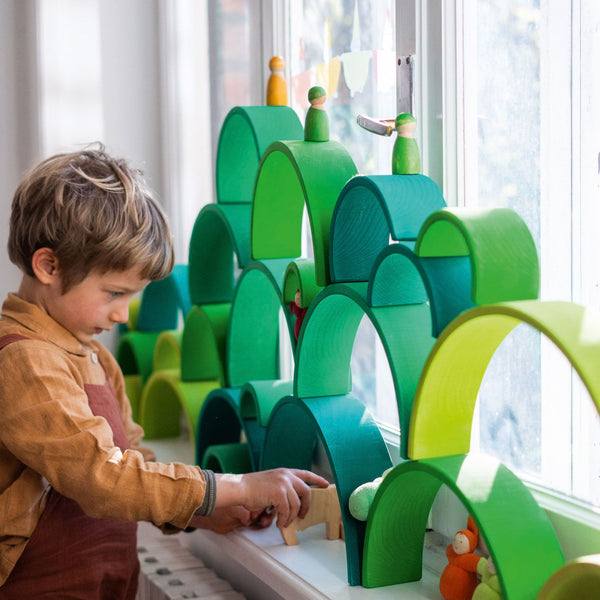 bambina che gioca con l'arcobaleno steineriano in legno creando minimondi