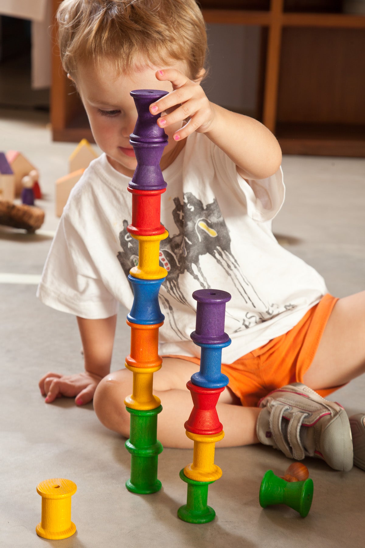 Bambino che gioca con delle bobine di legno