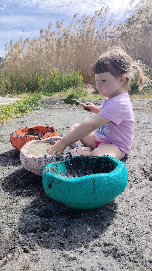 Bambina che gioca con la sabbia al lago con gli stapelstein