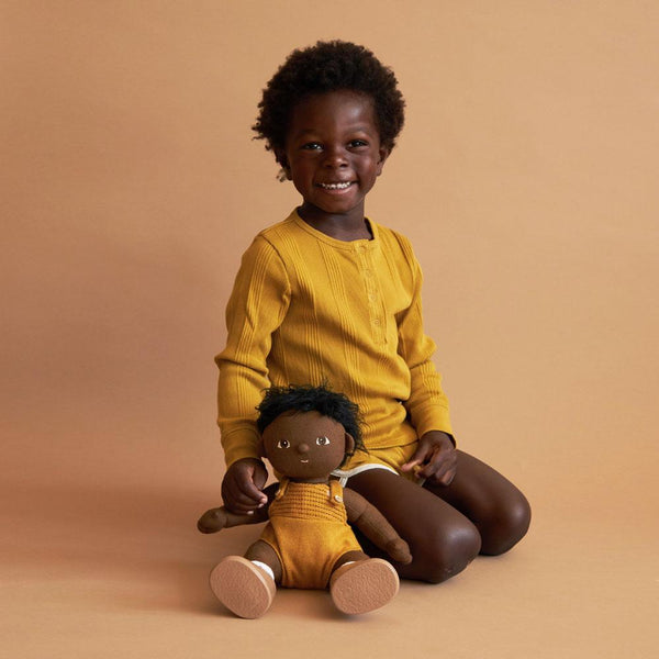Bambino con la sua bambola Minikane, la bambola ed il bambino hanno la stessa etnia il bambino sorride