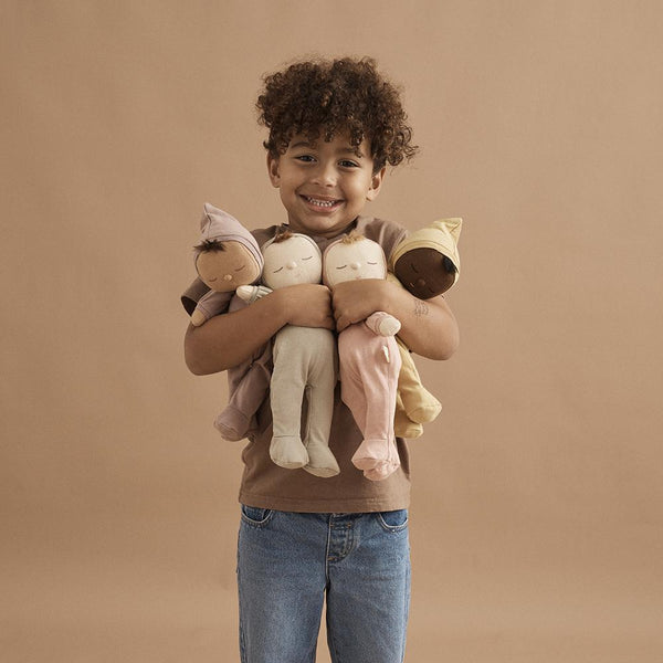 Bambino maschio che abbraccia delle bambole Dinkum di Olli Ella