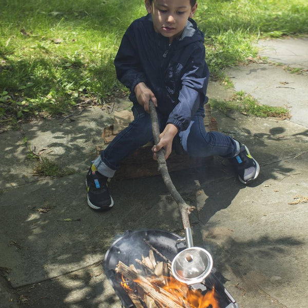 Bambino che cuoce popcorn sul fuoco all'aperto