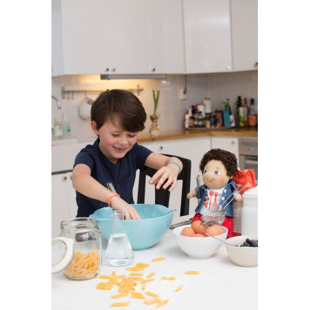 Bambino che cucina con la sua bambola divertendosi. La bambola è una Rubens Barn Activity 