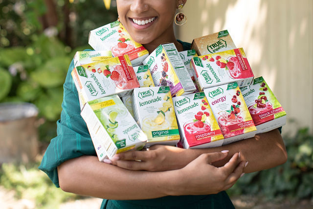 Woman holding True Citrus products in the summer