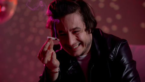 smiling man in a black leather jacket with marijuana