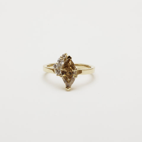 A custom engagement ring featuring an antique champagne marquise diamond and pear and round diamonds in 14k yellow gold.