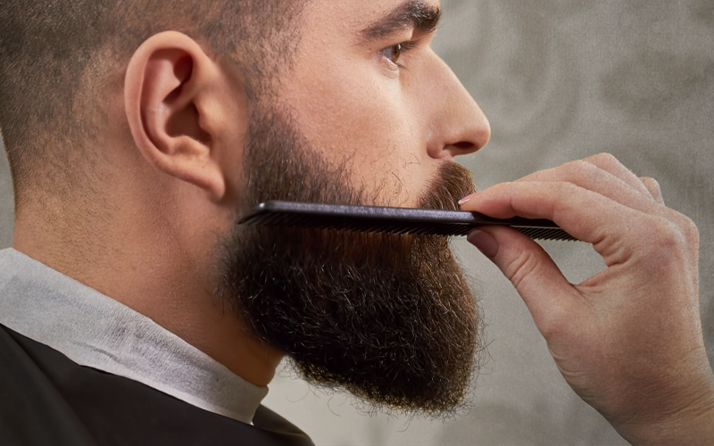 Man in side view combing his full beard