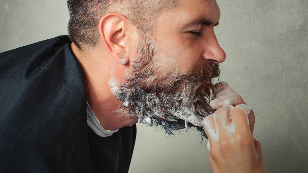 Man leaning forward to the hands washing his beard