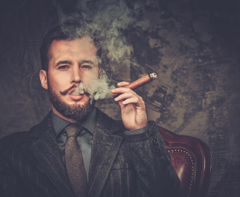 man in suit with beard smoking a cigar