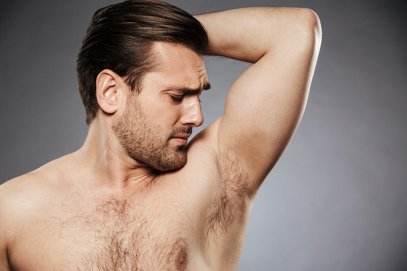 Man looking at his hairy armpit with dissaproval