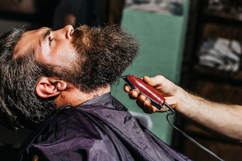 man wit thick beard getting a shave