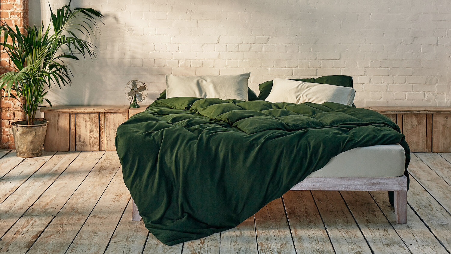 sage green and dark green bedding mix and match on bed in a modern room