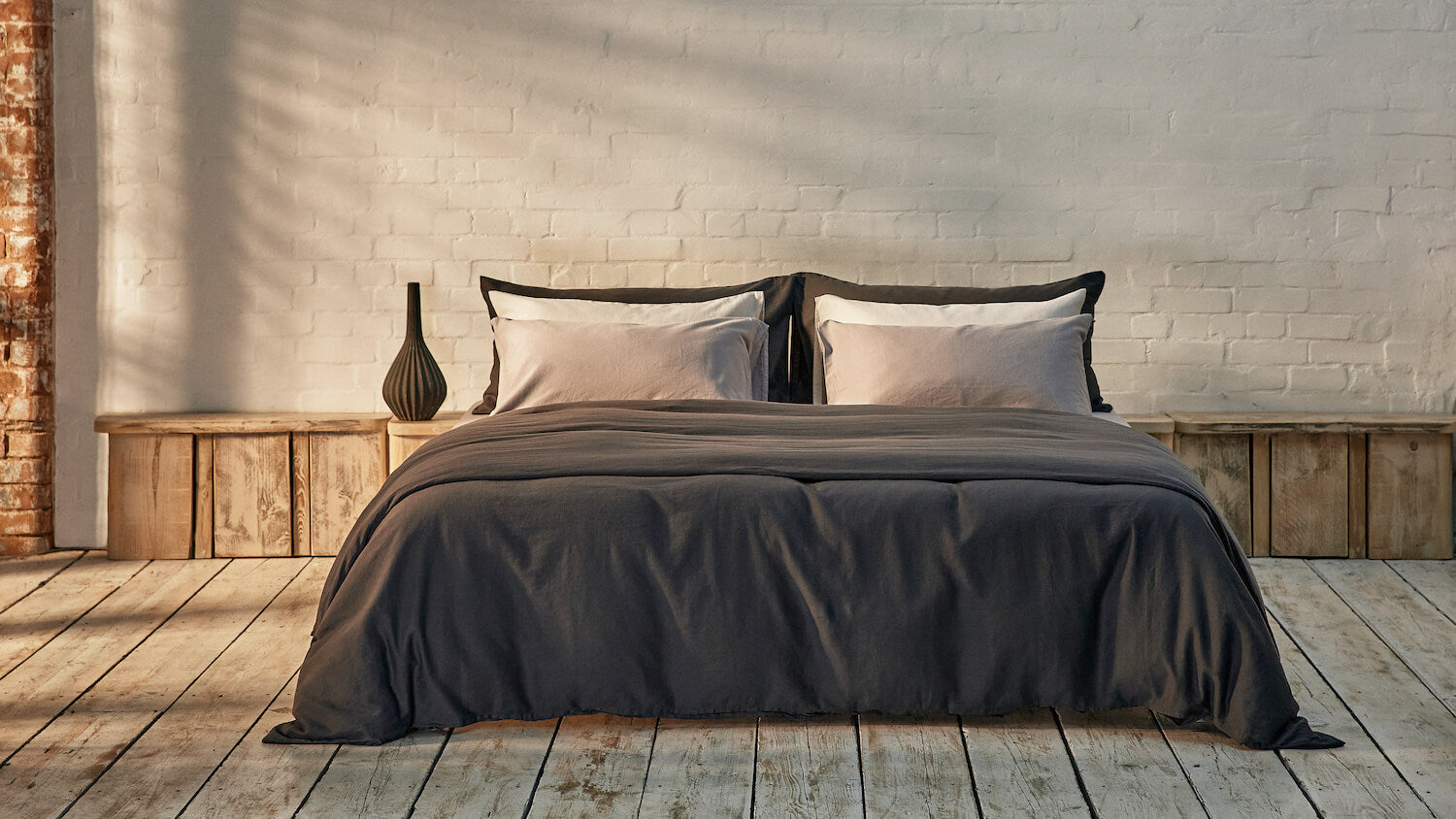 dark grey and light grey bedding mix and match on bed in a modern room