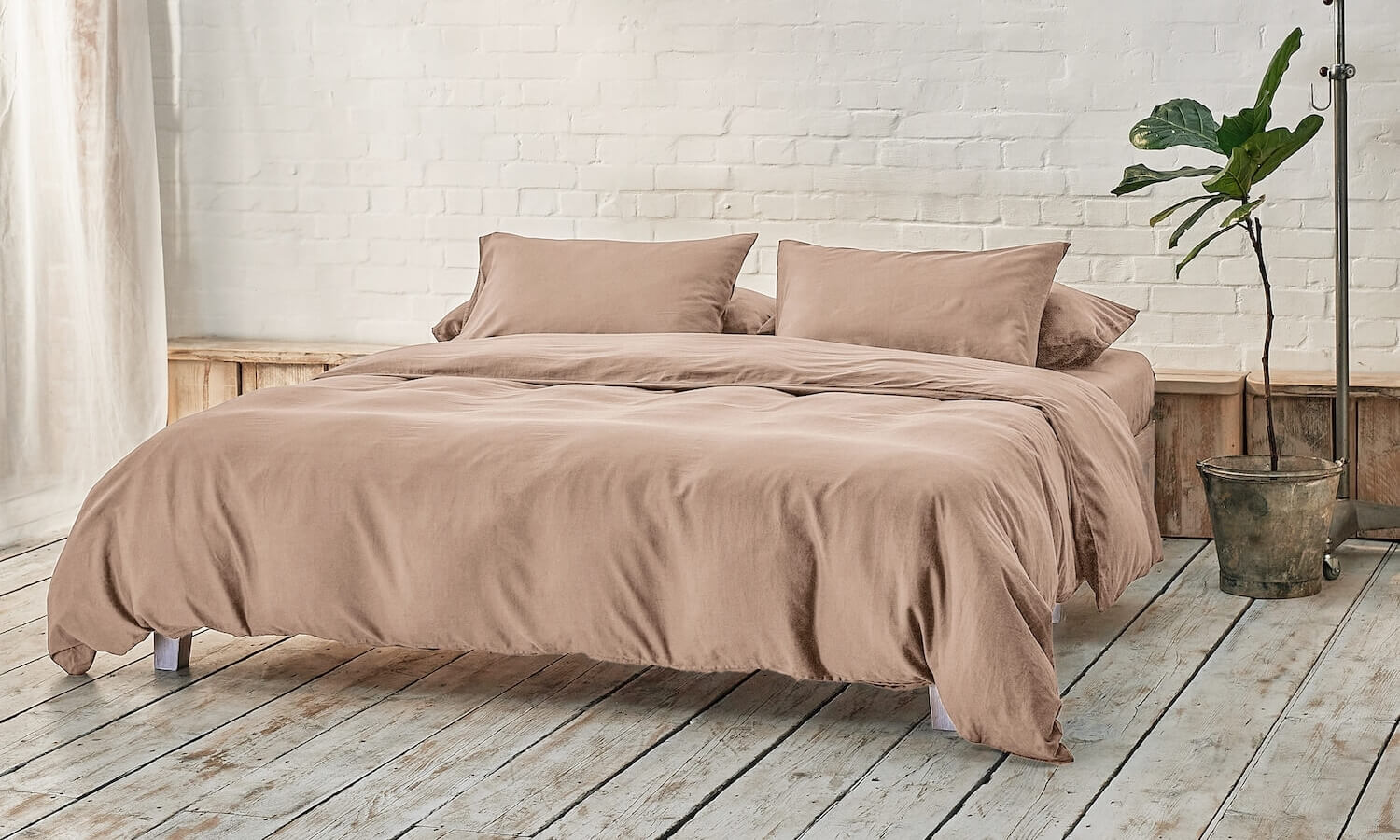 beige duvet cover, two pillowcases, and bottom sheet on double bed in apartment with plant and wooden flooring