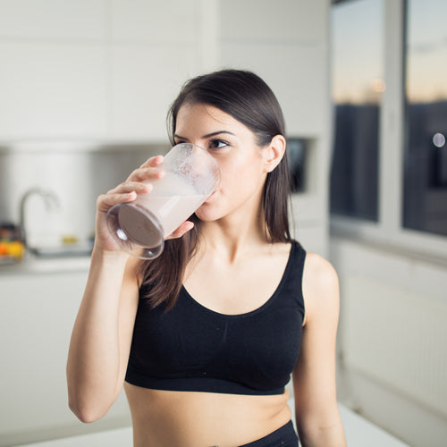 a lady is drinking smoothie after working out