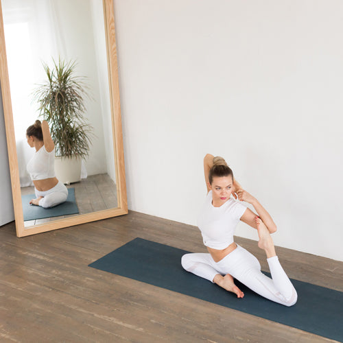 a lady is stretching in front of a mirror