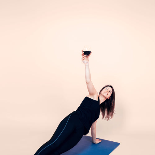 a lady is doing workout with another hand holding a wine glass