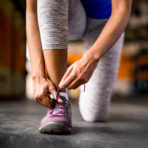 a woman is tying her shoes