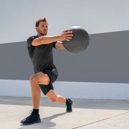 man performing lunge while holding medicinal ball