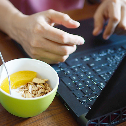 a person is eating while working in front of laptop