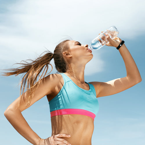 a woman is drinking water after workout