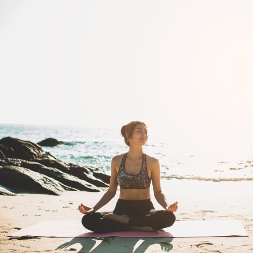 a lady is doing yoga on beach